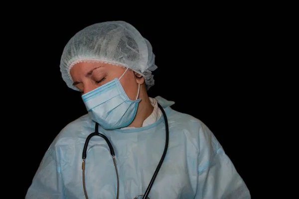 Doktor ya da hemşire uykusunun ayrı bir görüntüsü. Coronavirus COVID-19 salgını. Üniformalı yorgun ve bitkin bir kadın ağır iş sonrası hastanede ya da klinikte uyuyor. Boynunda steteskop ve gözleri kapalı bir kadın.