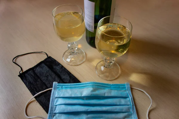 Salgın bir dünyada aşk macerası. Masada iki bardak ve bir şişe şarap ve iki tıbbi maske var. Tecrit karantinasına bağlı olarak yeni zaman ve yaşam tarzı değişimi kavramı 