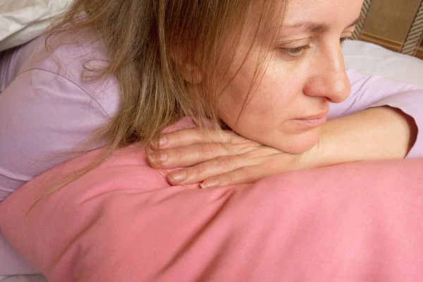 Kadın duyguları. Yatakta orta yaşlı beyaz kadın portresi. Kız hayatını düşünüyor. Yüz ifadesi ve psikoloji.