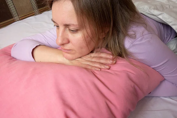 Kadın duyguları. Yatakta orta yaşlı beyaz kadın portresi. Kız hayatını düşünüyor. Yüz ifadesi ve psikoloji.