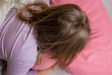 Kadın duyguları. Yatakta orta yaşlı beyaz kadın portresi. Kız yastıkta ağlıyor. Psikolojik sorunlar ve yalnızlık.