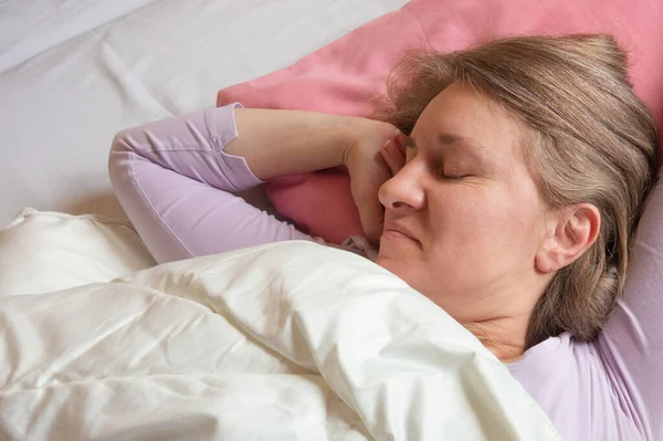 女は後ろで寝ている 40歳の女性のクローズアップポートレートで落ち着いたとリラックスした顔の睡眠ピンクの枕 — ストック写真