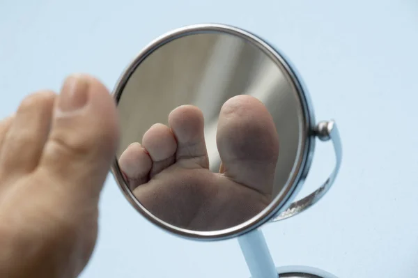 Persoon die naar de voetzool in een spiegel kijkt. — Stockfoto