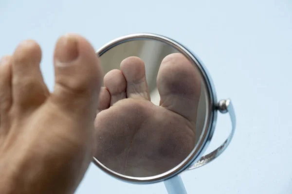 Person looking at the sole of the foot in a mirror. — Stock Photo, Image