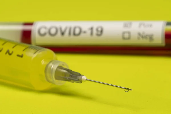 syringe with needle drop and a blood tube with covid-19 label.