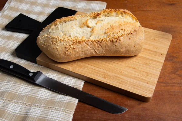 Kırsal ahşap arka planda susamlı ev yapımı Fransız ekmeği.
