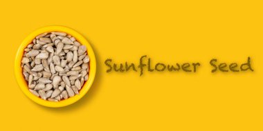 Sarı zemin üzerinde ayçiçeği tohumu olan bir kâse.