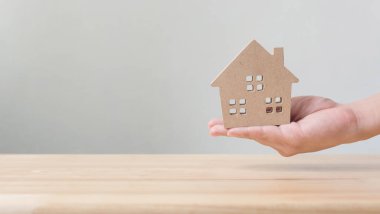 Property investment and house mortgage financial concept, Hand holding wooden home