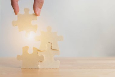 Hand of male or female putting jigsaw puzzle connecting on wooden desk, Strategic management and business solutions for success