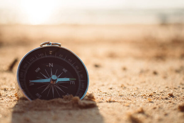 Compass is placed on the beach and sunshine in the evening sunse