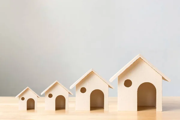 La inversión inmobiliaria y el concepto financiero de la hipoteca de la casa, casas de madera dispuestas diverso tamaño en fila en tabla de madera — Foto de Stock
