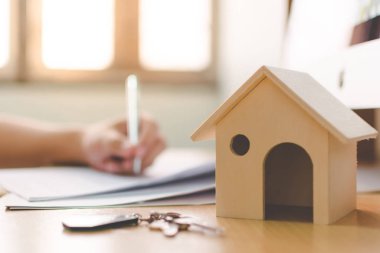 Ahşap ev modeli ve anahtar ev ahşap masa üzerinde elle imzalanmış belge sözleşme kredisi veya ipotek emlak yatırımı