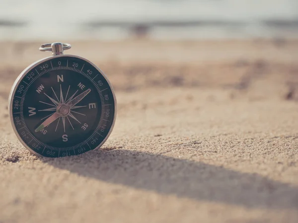 Brújula se coloca en la playa y el sol en el atardecer —  Fotos de Stock