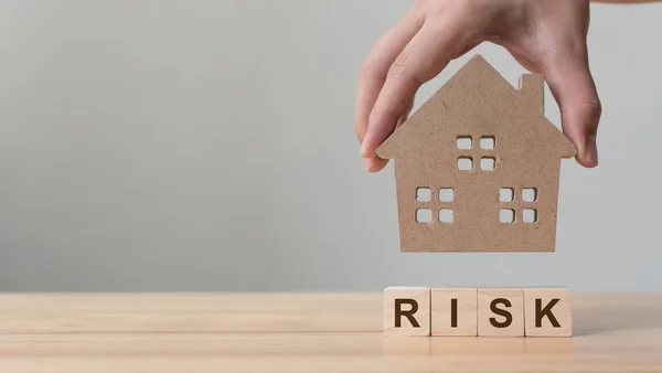 Investice do nemovitostí a hypotéky na bydlení. Koncept řízení rizik. Ruční kladení dřevěných domů na dřevěný blok se slovem "riziko" — Stock fotografie
