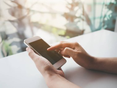 El ele tutuşan ve beyaz cep telefonuna dokunan beyaz ekran siyah akıllı telefonun görüntüsü.