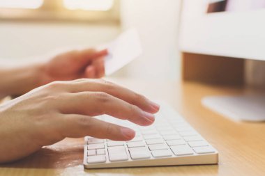 Kredi kartını tutarak ve bilgisayar masaüstünü kullanarak. Çevrimiçi alışveriş ödemesi ve e-ticaret kavramı