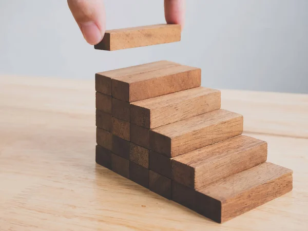 Hand arranging wood block stacking as step stair. Ladder career path concept for business growth success process, Copy space