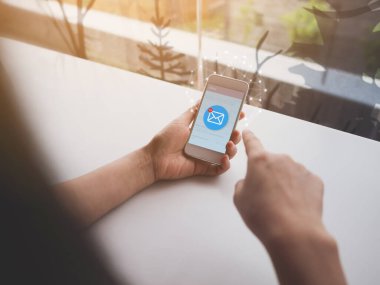 Cep telefonunda e-posta ikonu olan bir kadın. E- posta pazarlaması veya bizimle iletişim kurma kavramı.