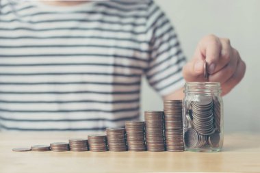 Hand of male putting coin in jar with money stack step growing growth saving money, Concept finance business investment