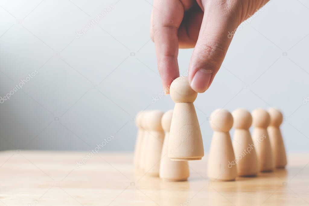 Human resource, Talent management, Recruitment employee, Successful business team leader concept. Hand chooses a wooden people standing out from the crowd.