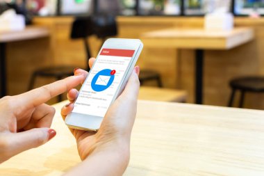Akıllı telefondan başvuru maillerini kontrol eden bir kadın eli. Akıllı telefondan yeni iletiler bildiriliyor