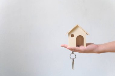 Elle tutulan ahşap ev ve ev anahtarlığı. Emlak yatırımı ve konut kredisi finansal emlak kavramı