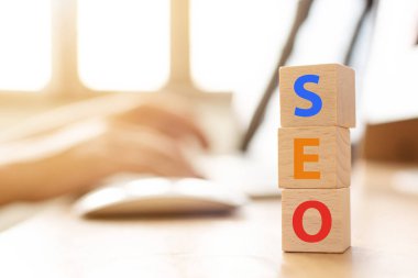 Arama motoru optimizasyon konsepti. Kelime SEO ile ahşap küp şeklinde dizüstü bilgisayar kullanan el bilgisayarı