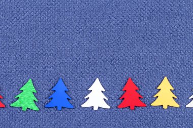 Christmas card with colorful  Christmas trees on a background of blue fabric clipart