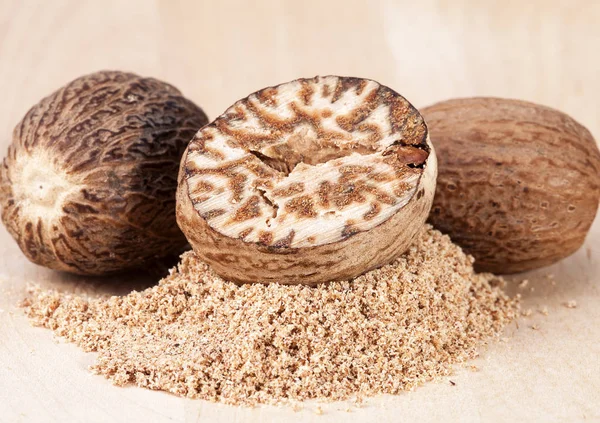 Nutmeg , whole and half on wooden plank, close up — Stock Photo, Image