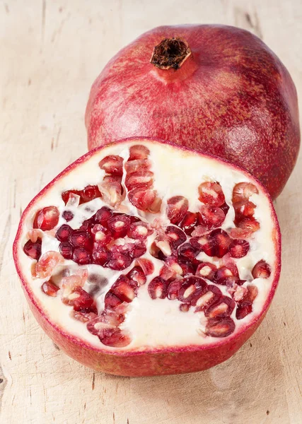 Fruit of red pomegranate on wooden plank, close up. — Stock Photo, Image