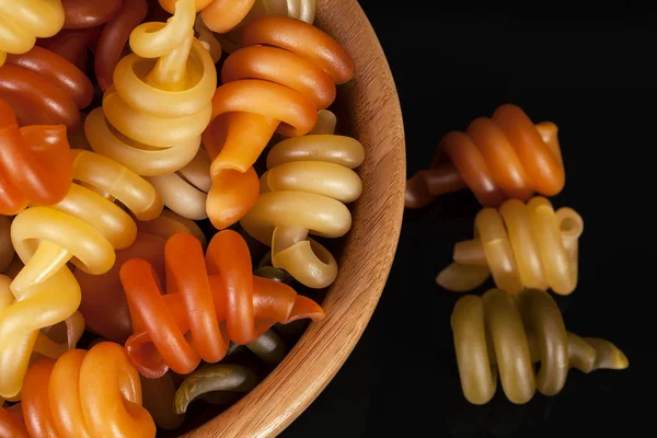 Spiral pasta trottole tricolore in wooden bowl  isolated on black  background — Stock Photo, Image