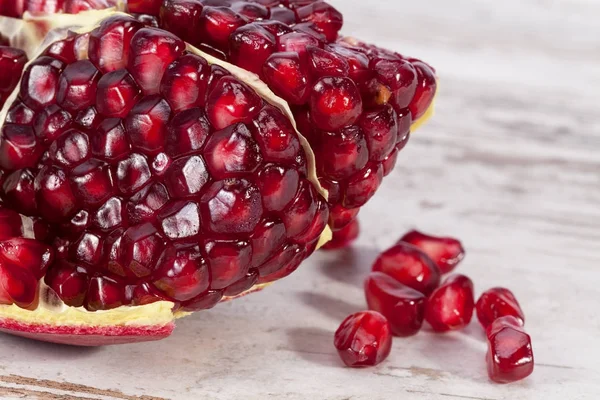 Fruit of red pomegranate on wooden plank, half with seeds — Stock Photo, Image