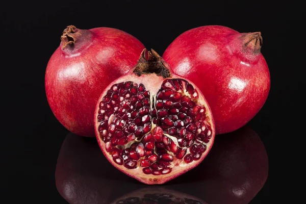 Frucht roter Granatapfel auf schwarzem Hintergrund, halb und ganz — Stockfoto