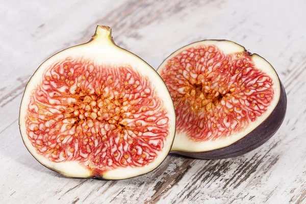 Fruits of half fresh figs on wooden plank, close up. — Stock Photo, Image