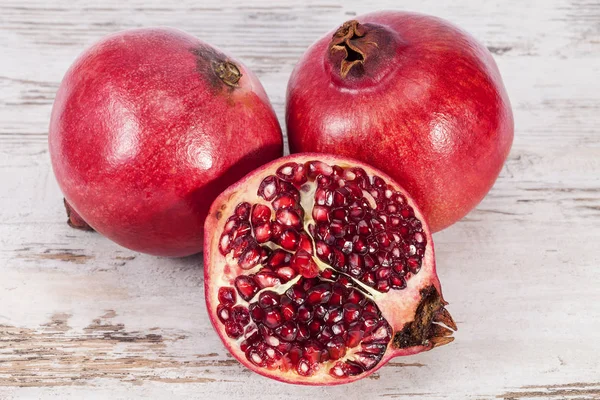 Früchte von rotem Granatapfel auf Holzplanke, zur Hälfte mit Kernen — Stockfoto