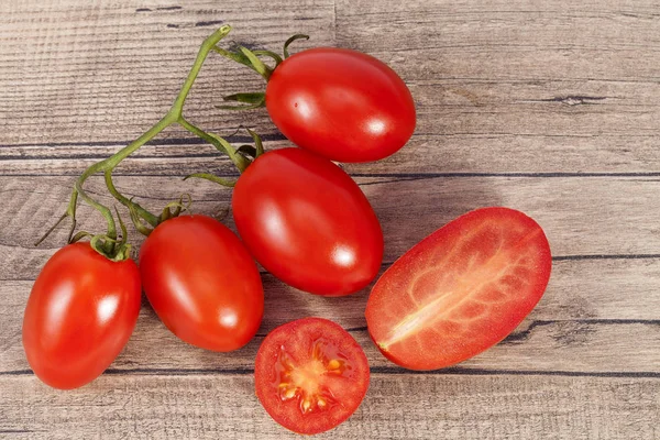 Hortalizas de tomates frescos, enteras y seccionadas, sobre tabla de madera — Foto de Stock