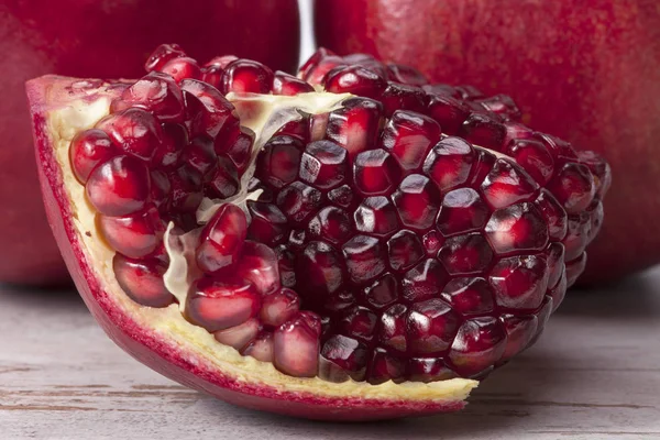 Fruit of red pomegranate on wooden plank, half with seeds — Stock Photo, Image