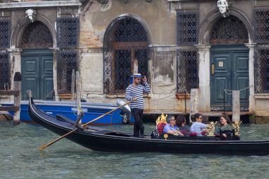 Venetian gondolier rowing gondola with tourists through the Grand Canal, Venice, Italy clipart