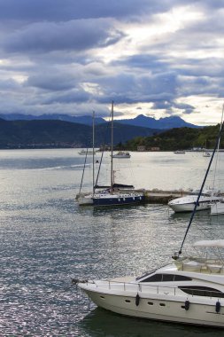 Gün batımında deniz kenarı ve limanda tekneler, fırtınalı gökyüzü, Porto Venere, İtalya