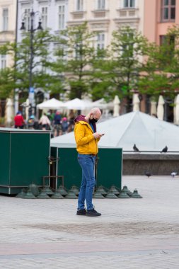 Krakow; Polonya - 2 Mayıs 2020: koruyucu maskeli bekar bir adam. Coronavirüs salgını sırasında Ana Pazar Meydanı, turist yok.. 