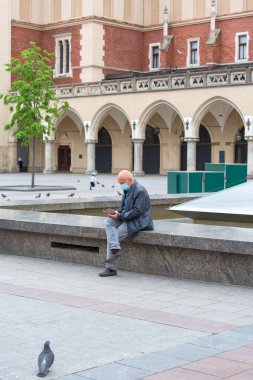 Krakow; Polonya - 2 Mayıs 2020: Koruyucu maskeli adam. Coronavirüs salgını sırasında ana pazar meydanı, turist yok. Kapalı durum sınırları