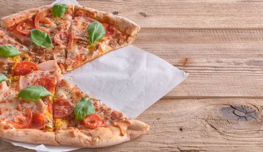 Güzel taze pizza jambon ve ahşap arka plan üzerinde domates