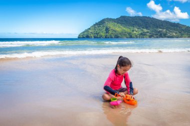 Küçük kız Maracas Bay Beach Trinidad 'da kumla oynuyor.