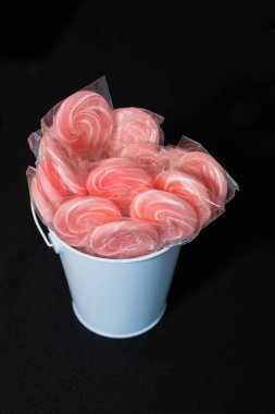 Lolipop şekeri beyaz kovanın içinde, siyah arka plan masasının üstünde.