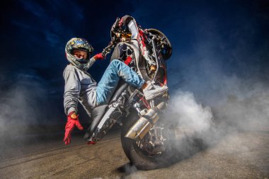 Moto rider making a stunt on his motorbike clipart