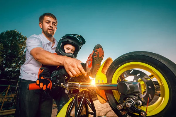 Treinador ensina pequenos motociclistas a fazer acrobacias em uma motocicleta — Fotografia de Stock