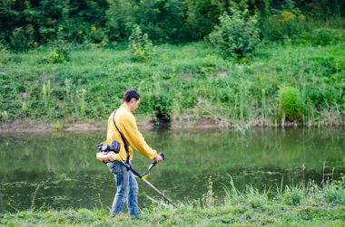 Park River yakınlarında metal dedektörüyle yürüyen bir adam. 