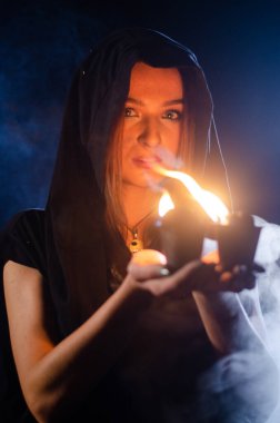 Gizemli genç kız siyah pelerin giyiyor, cadıların Şenlik ateşinin yanındaki ormanda Şabat günü
