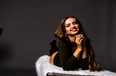 Güzel dansçı. Kız model. Kız bir şapkanın içinde oturuyor ve masaya oturuyor. Güzel iç çamaşırlı bir kız. Kız masada oturuyor ve maskaralık yapıyor, surat asıyor. pürüzsüz, bakımlı bacaklar.