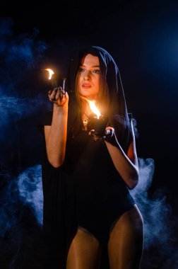 Gizemli genç kız siyah pelerin giyiyor, cadıların Şenlik ateşinin yanındaki ormanda Şabat günü